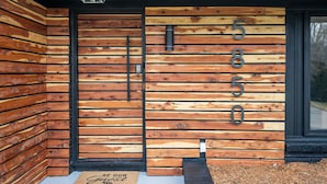 Fachada de edificio moderna con diseño de paneles de madera y una puerta negra.