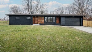 Una casa moderna de dos pisos con garaje, un porche delantero y un césped bien cuidado.