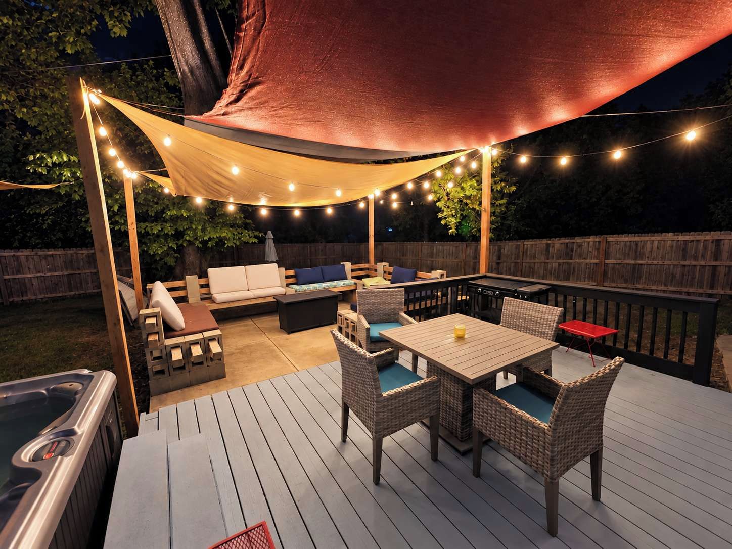 Une terrasse extérieure dotée d’un jacuzzi, d’un espace salon et de guirlandes lumineuses.