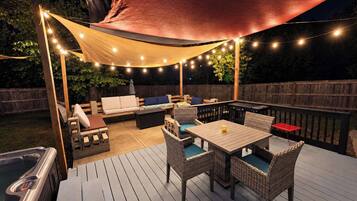 Une terrasse extérieure dotée d’un jacuzzi, d’un espace salon et de guirlandes lumineuses.
