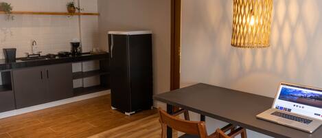 Una cocina moderna con un refrigerador negro, armarios de madera y una zona de comedor con una computadora portátil sobre una mesa.