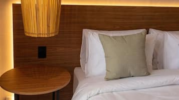 A hotel room with a wooden headboard, a round wooden table, and a bed with white bedding and a green pillow.