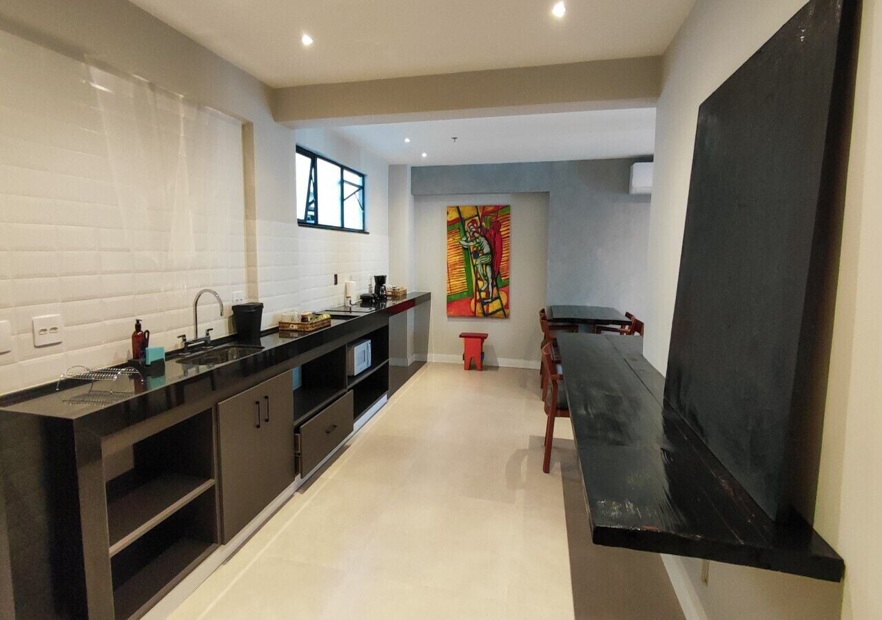 A modern kitchen with black countertops, white tiles, and a red stool.