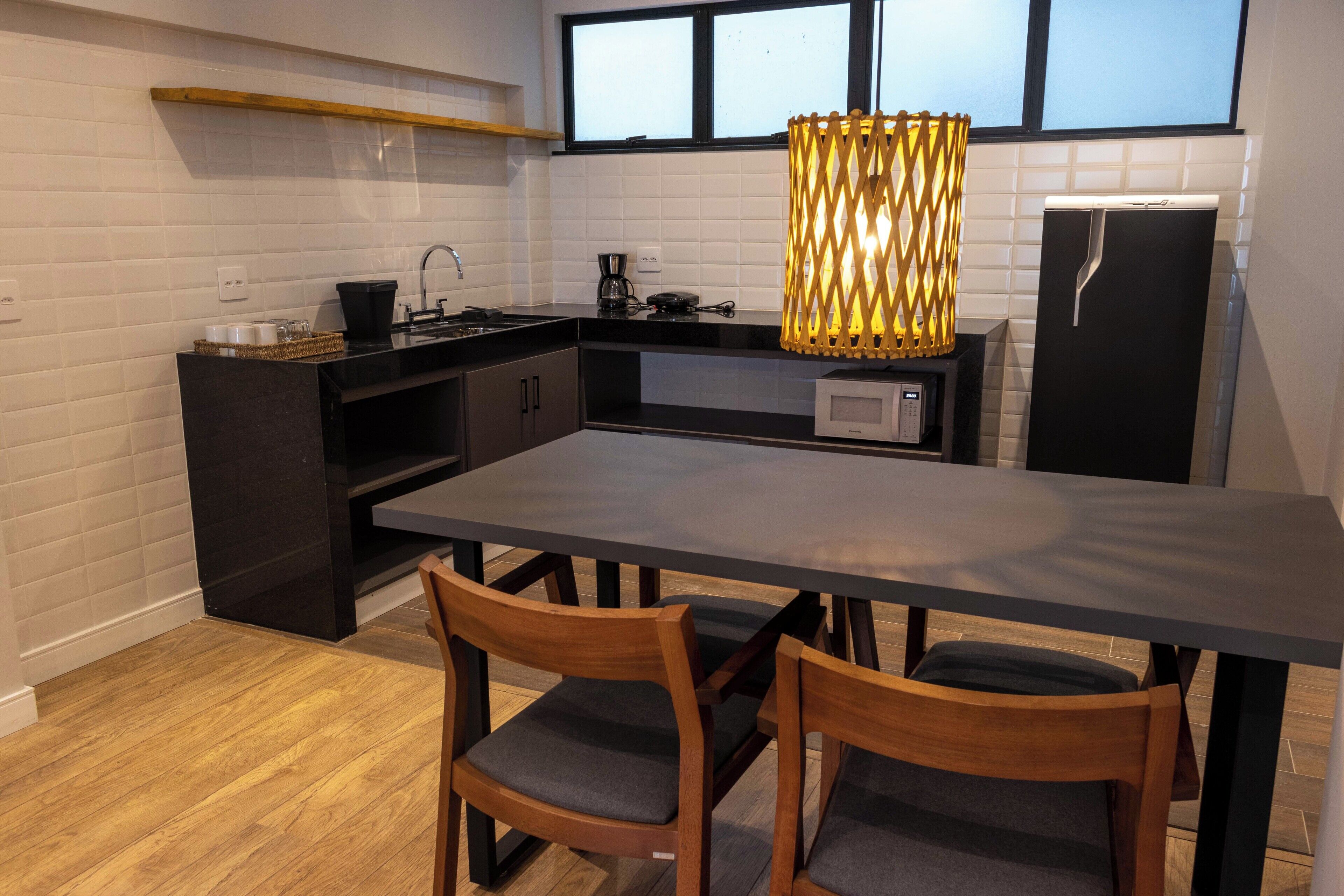 A modern kitchen with a dark countertop, wooden chairs, and a large table.