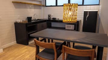 A modern kitchen with a dark countertop, wooden chairs, and a large table.