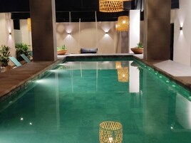 Una piscina con sillones de descanso y plantas en macetas.