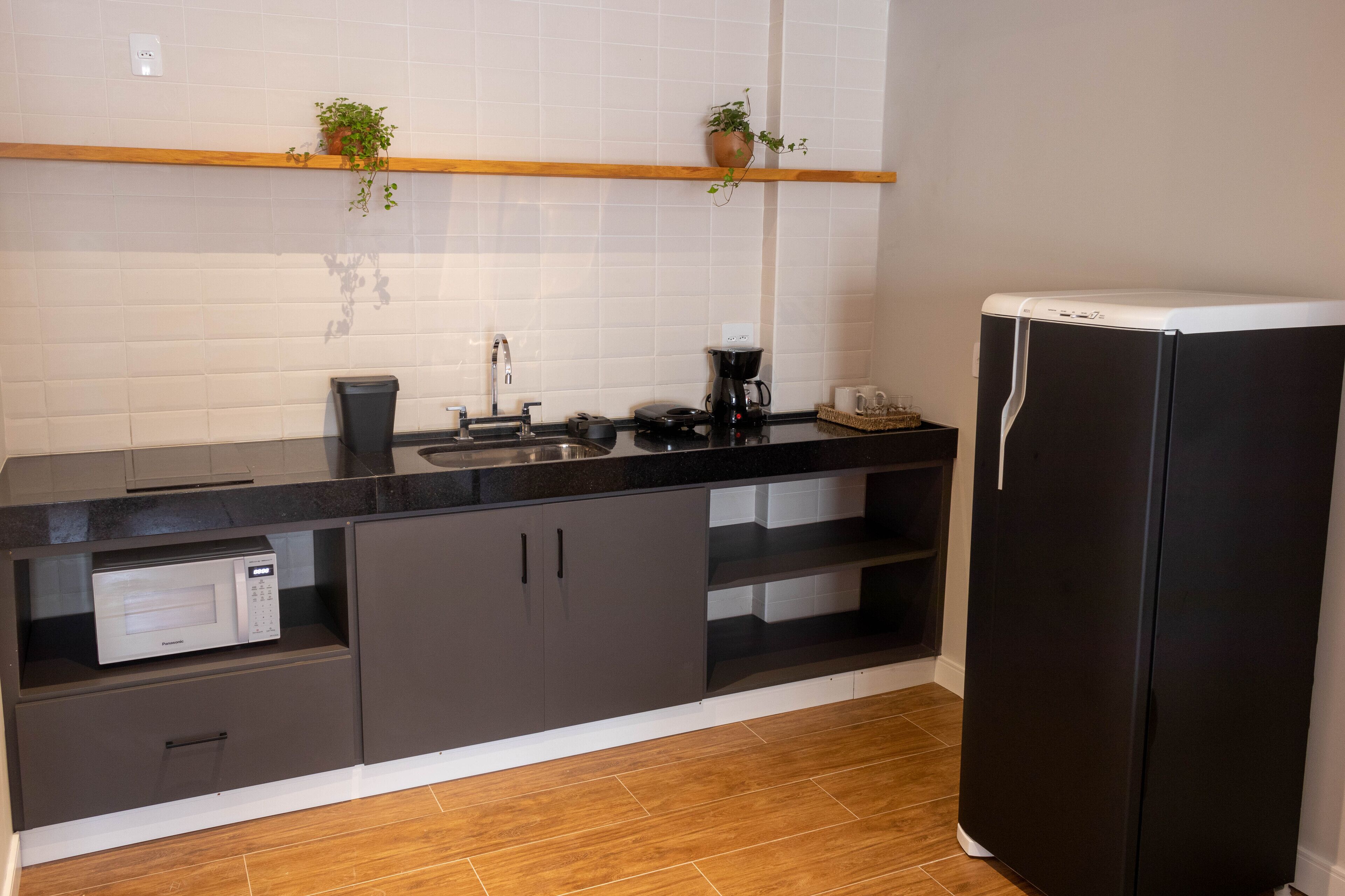 A modern kitchen with a black refrigerator, a microwave, a coffee maker, and a sink.