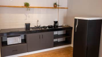 A modern kitchen with a black refrigerator, a microwave, a coffee maker, and a sink.