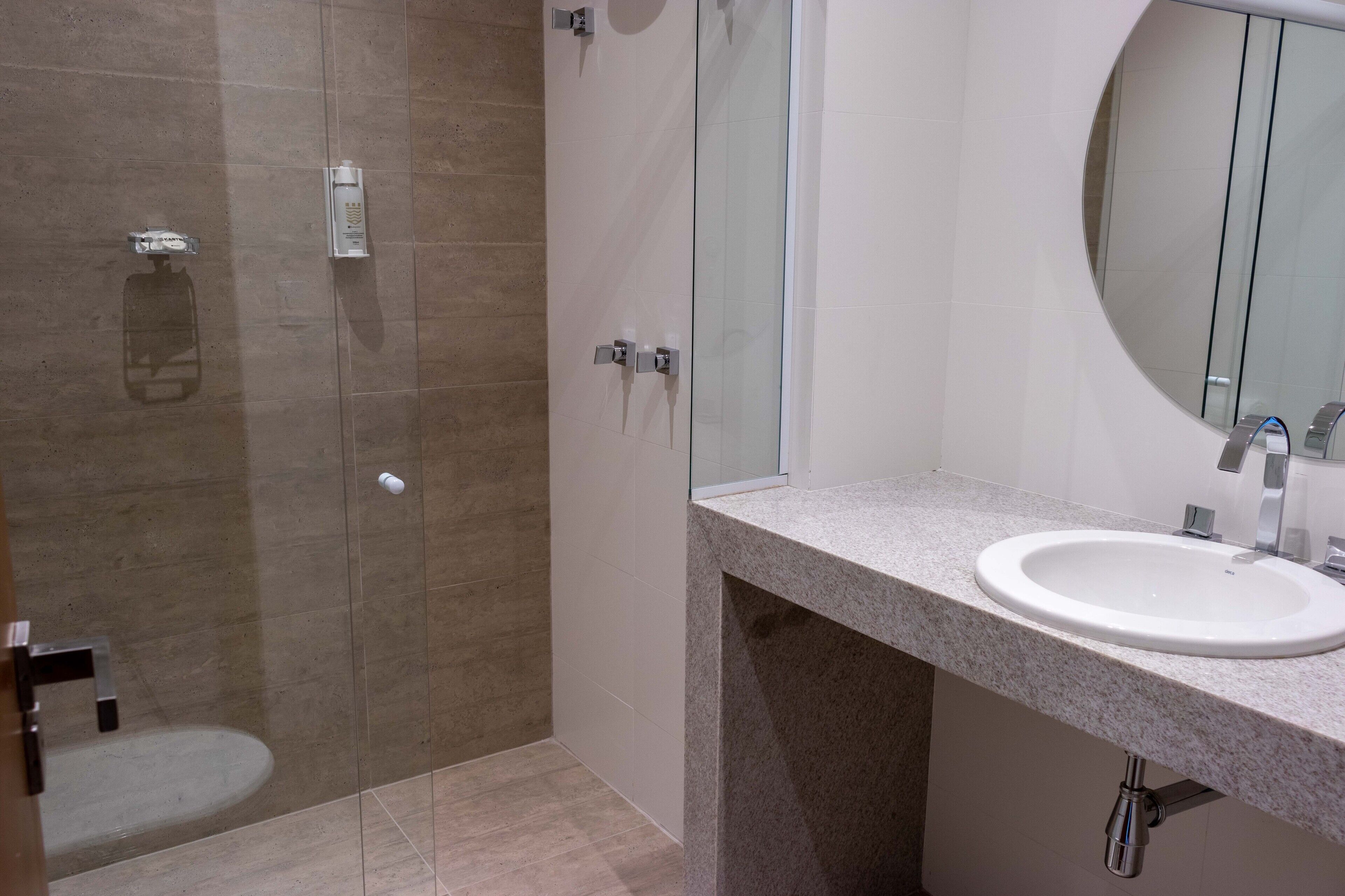 A modern bathroom with a glass shower enclosure, a sink with a mirror, and a toilet.