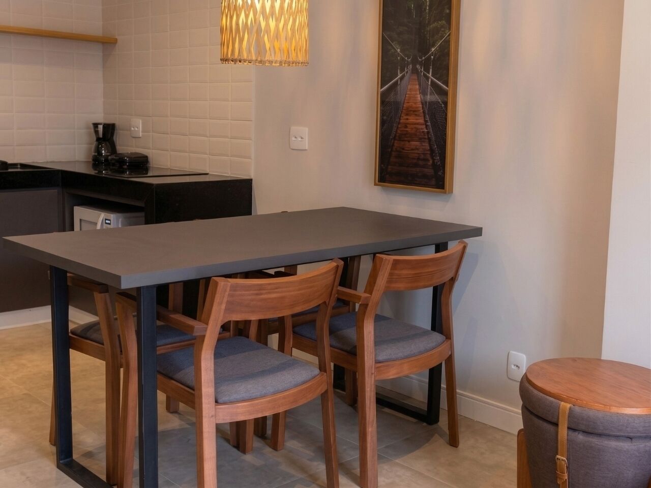 A dining area with a rectangular table and four wooden chairs with grey cushions.