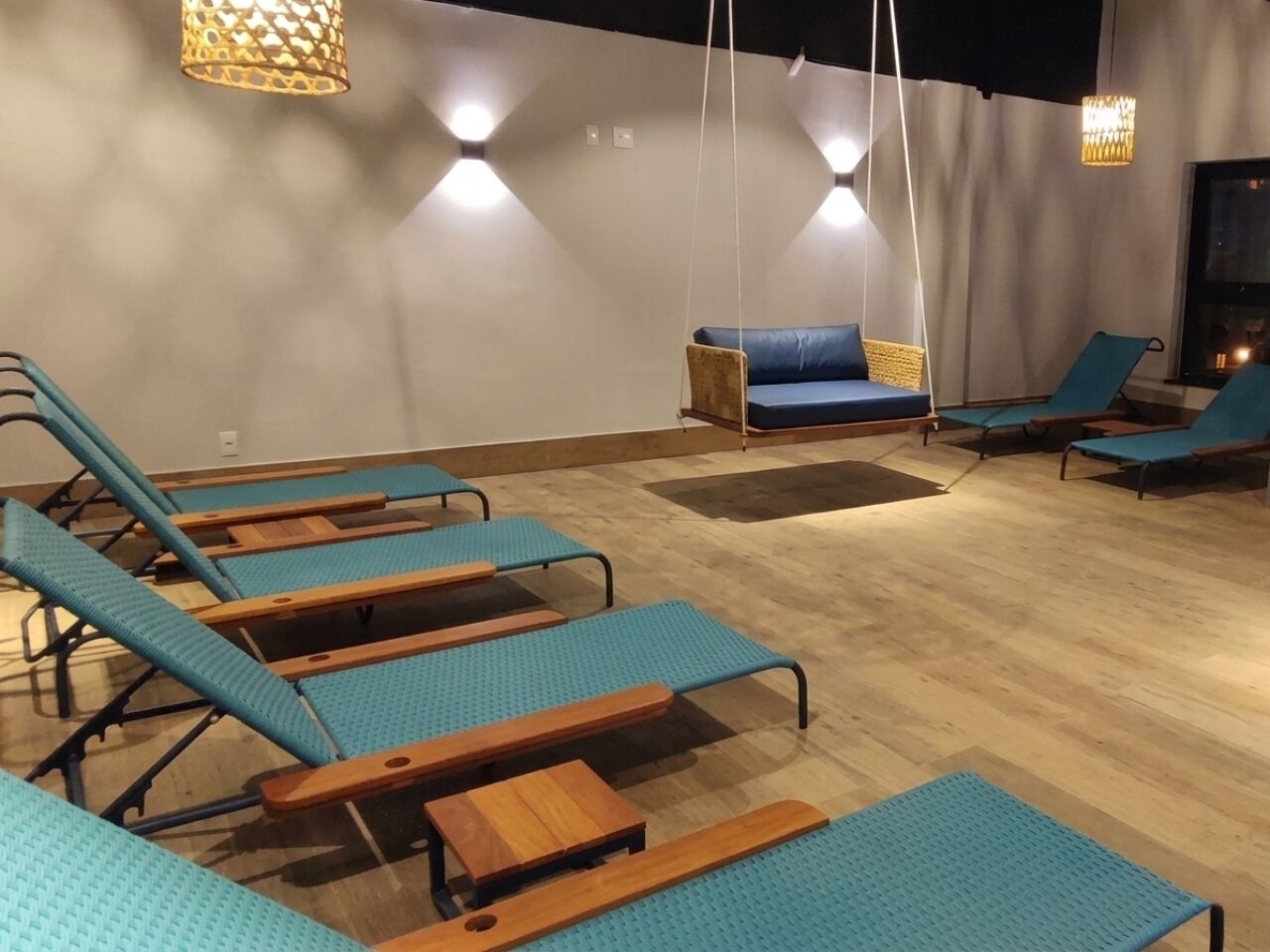 Ein Raum mit mehreren blauen Lounge-Sesseln, einem blauen Sofa und hängenden Lampen.