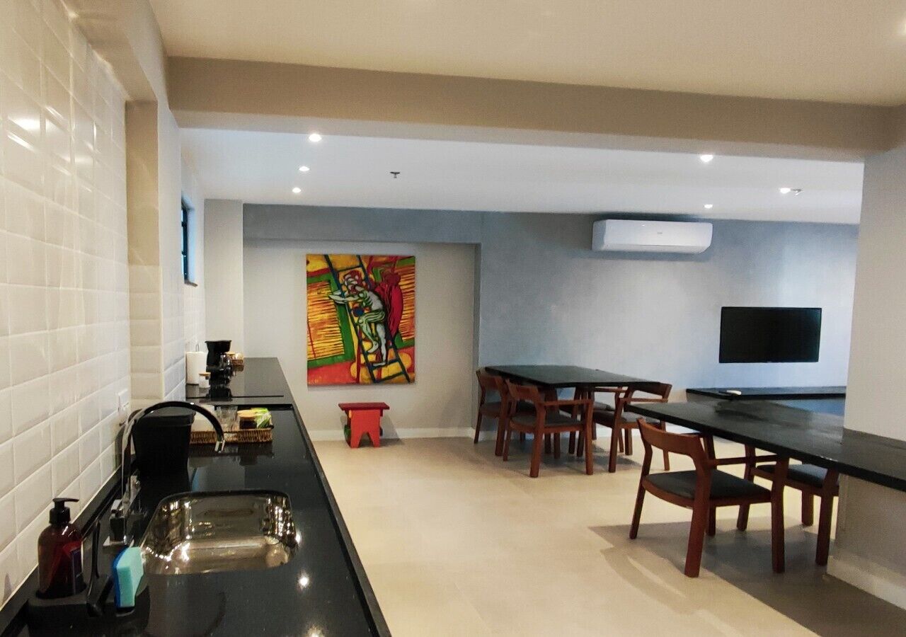 A modern kitchen with a black countertop, a sink, and a colorful abstract painting on the wall.