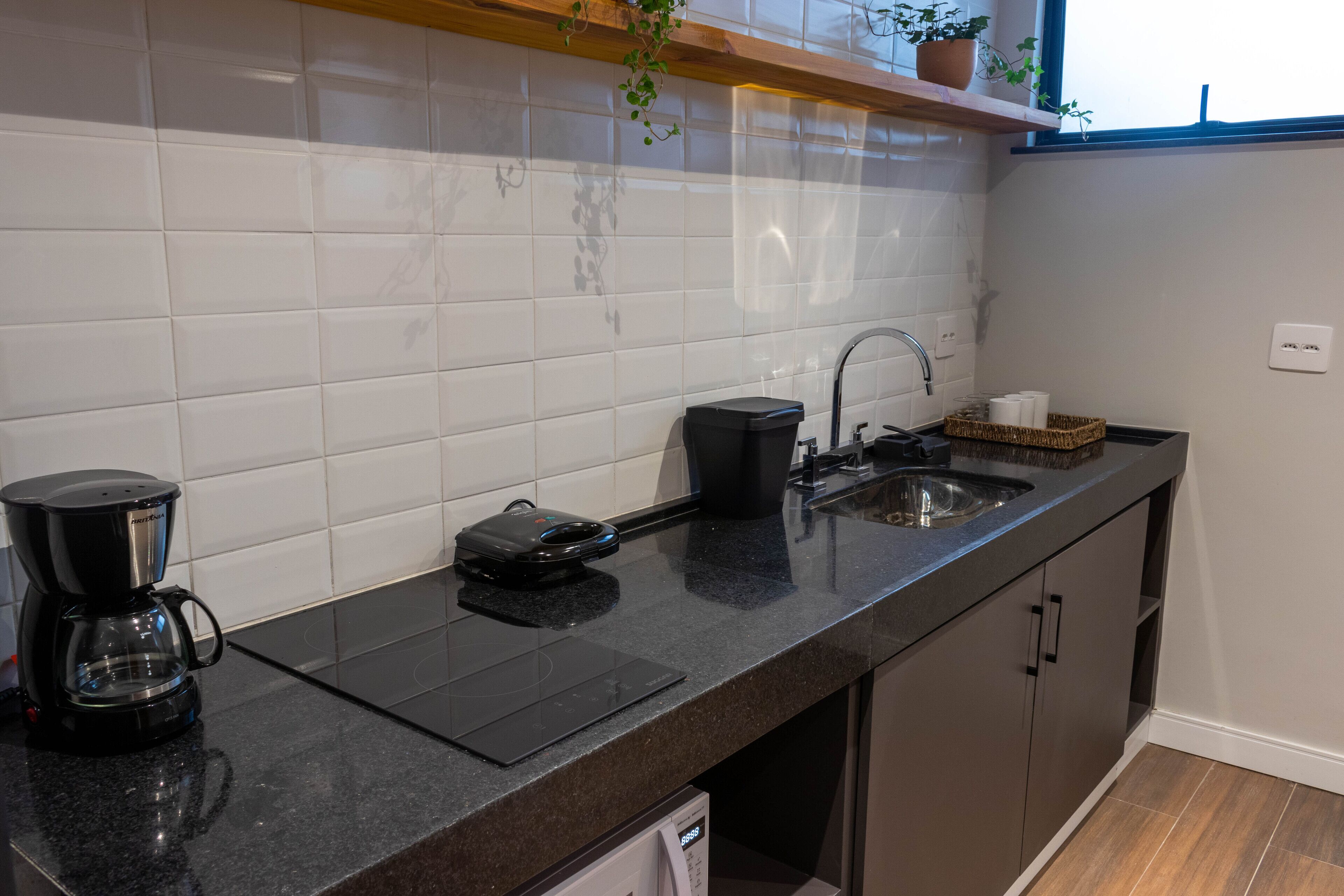 A modern kitchen with a black countertop, a coffee maker, a toaster, and a sink.