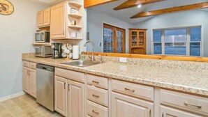 A kitchen with granite countertops, wooden cabinets, a dishwasher, a microwave, and a window with a view. - LAKEFRONT - Lake Escape - Arrowhead Lake Community (Pocono Lake)