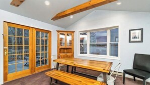 A dining area with a wooden table and benches, a black chair, and a cabinet with glass doors. - LAKEFRONT - Lake Escape - Arrowhead Lake Community (Pocono Lake)