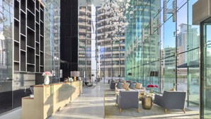 Een moderne lobby met een receptiebalie, een zithoek en grote glasramen met uitzicht op de stad.