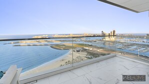 Een balkon met een helder uitzicht over een jachthaven, strand en stadsbeeld.