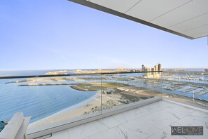 Enjoy unobstructed views of the marina, yachts, and beach from this apartment's spacious balcony.