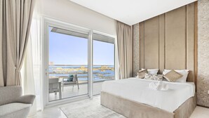 Een moderne hotelkamer met een groot bed, een bank en een balkon met uitzicht op de stad.