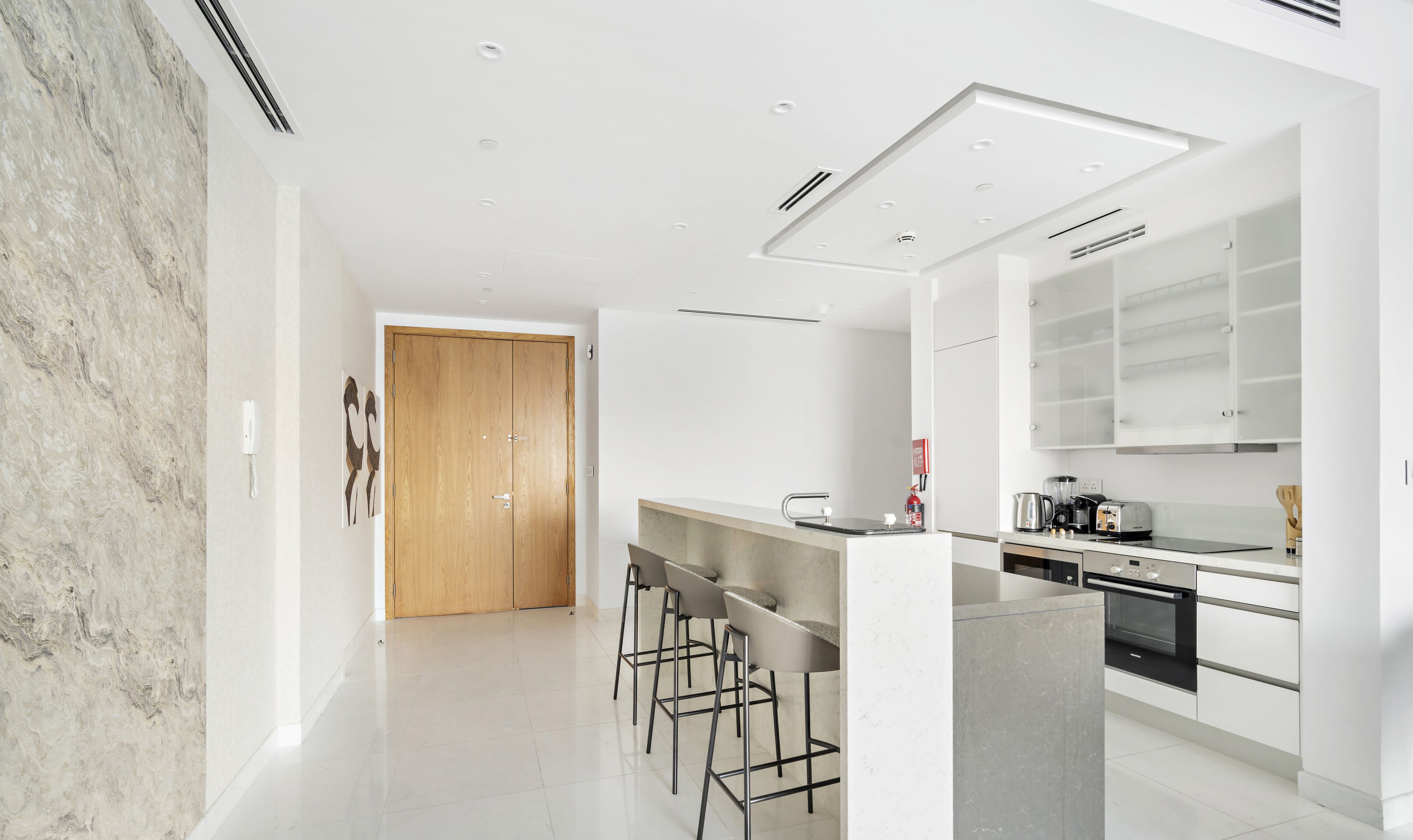 Una cocina moderna con una isla central, taburetes de bar y un horno empotrado.