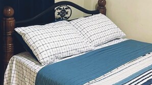 Un lit avec une couvre-lit à carreaux et une couverture bleue.