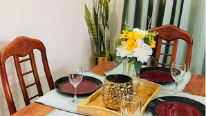 Une table à manger dressée avec des assiettes rouges et noires, des verres à vin et un vase décoratif rempli de fleurs.