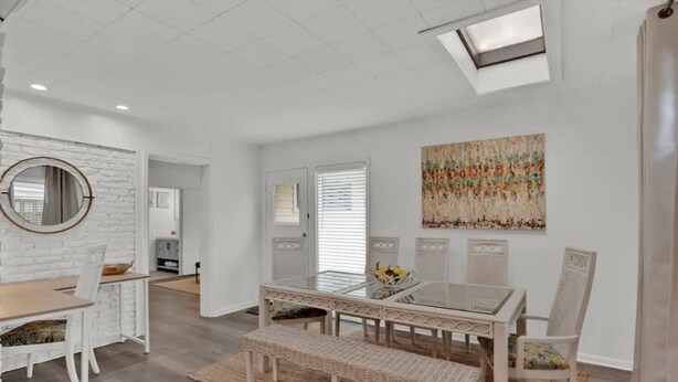 A modern dining area with a glass-top table, wicker bench, and white chairs. - Cheerful and chic- newly renovated home 4br/3b (Shreveport)
