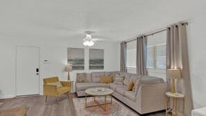 A living room with a sofa, armchairs, a coffee table, and a ceiling fan. - Cheerful and chic- newly renovated home 4br/3b (Shreveport)