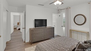 A bedroom with a bed, dresser, TV, ceiling fan, and a mirror. - Cheerful and chic- newly renovated home 4br/3b (Shreveport)