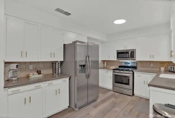Una cocina moderna con armarios blancos, electrodomésticos de acero inoxidable y piso de madera.