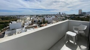 A balcony with a view of a cityscape, including buildings and a clear sky. - Condos Ferrara (Mazatlán)