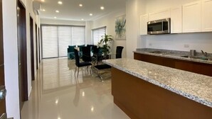 A modern kitchen with white cabinets, a granite countertop, and stainless steel appliances. - Condos Ferrara (Mazatlán)