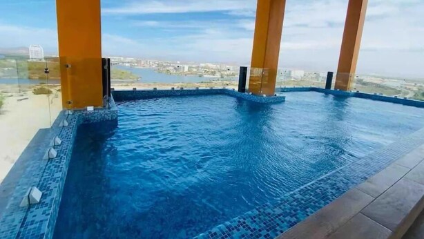 A rooftop infinity pool with a clear view of the city skyline. - Condos Ferrara (Mazatlán)