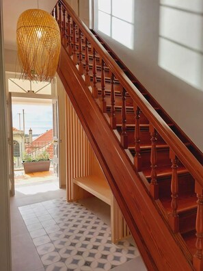 A wooden staircase with a patterned floor and a hanging light fixture.