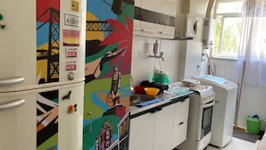 A kitchen with white cabinets, colorful artwork, a microwave, and a window with curtains.
