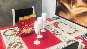 A dining area with a red tablecloth, white wine glasses, and a bag of snacks.