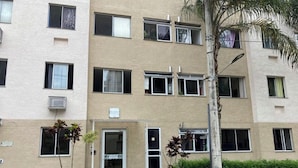 A multi-story building with a beige facade, multiple windows, and a door with a sign above it.