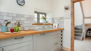 Une cuisine moderne avec un plan de travail en bois, des armoires blanches et des carreaux décoratifs sur le mur derrière l’évier.