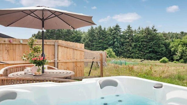 Un bain à remous avec une terrasse en bois et une clôture en bois en arrière-plan.