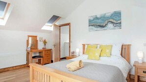 Une chambre à coucher avec un lit en bois, une table de chevet, une commode, un miroir et un tableau accroché au mur.