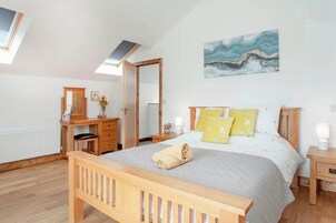 A bedroom with a wooden bed, a nightstand, a dresser, a mirror, and a painting on the wall.