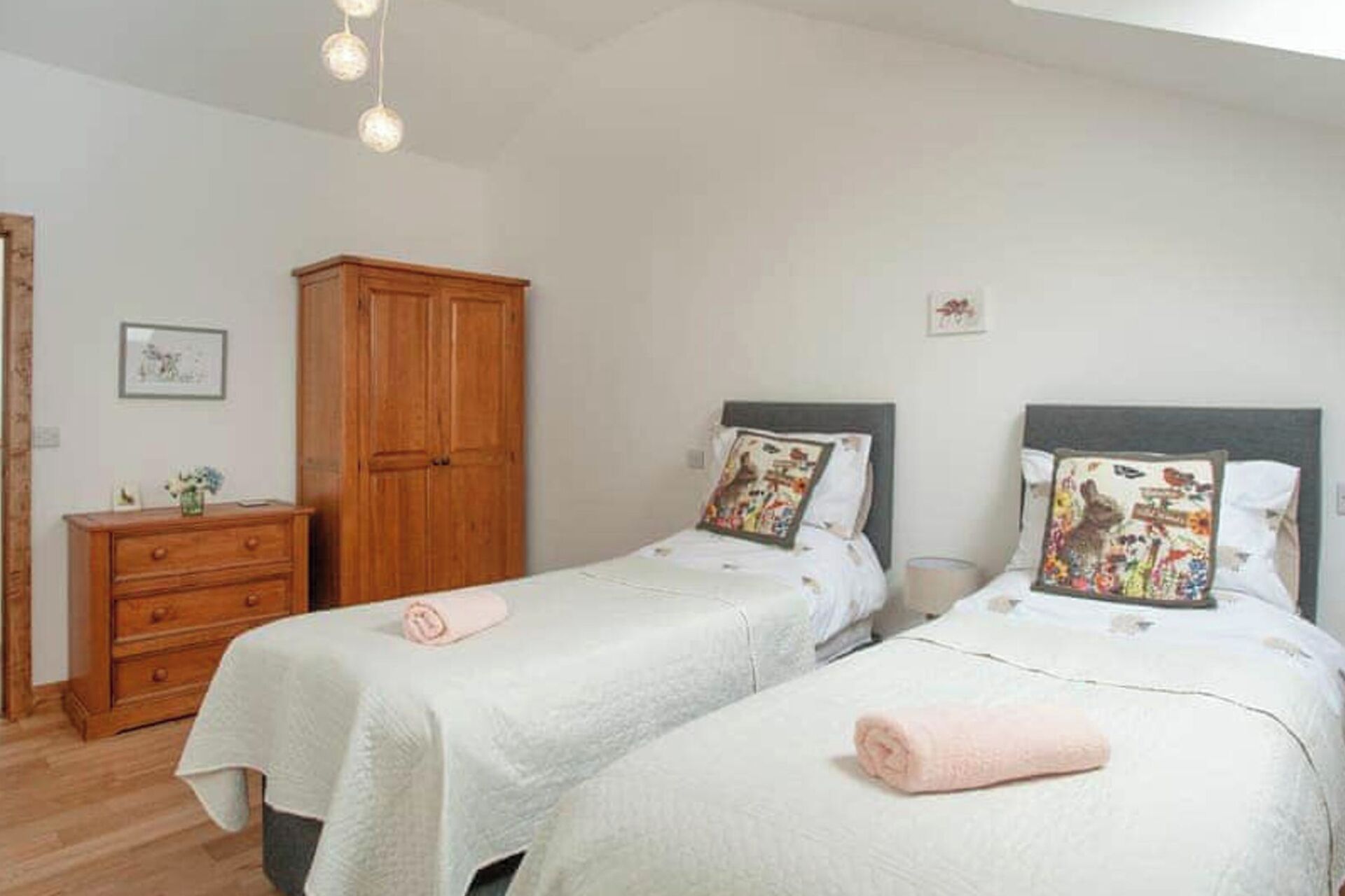 A bedroom with two beds, a wooden wardrobe, and a dresser.
