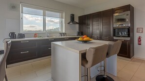 Una cocina moderna con una isla central, muebles oscuros y un ventanal con vistas.