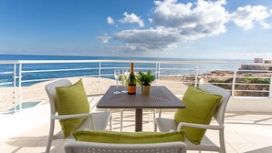 Una terraza con una mesa y dos sillas, con vistas a una playa y al mar.