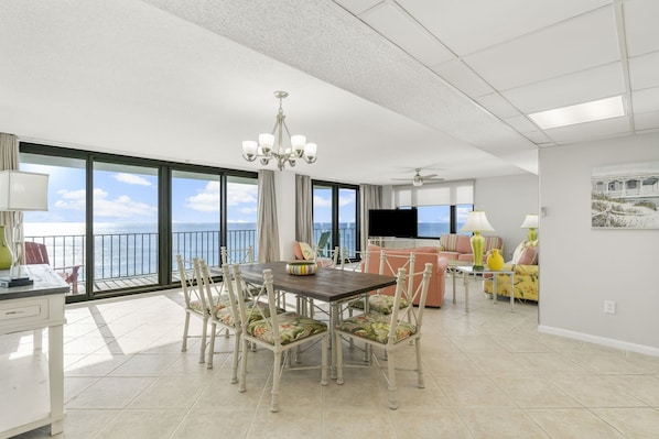 A spacious living area with a dining table, chairs, and a view of the ocean. - Oversized Gulf-Front Watercrest 2BR Sleeps 8 Private Balcony East End PCB (PCB)