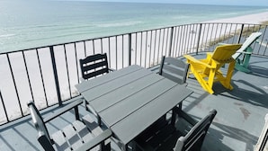 Varanda com mesa e cadeiras, vista para uma praia e oceano.