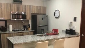 Una cocina moderna con una isla central, electrodomésticos de acero inoxidable y un reloj en la pared.