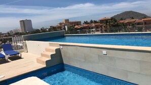 Una piscina con vistas despejadas a los edificios circundantes y una montaña al fondo.