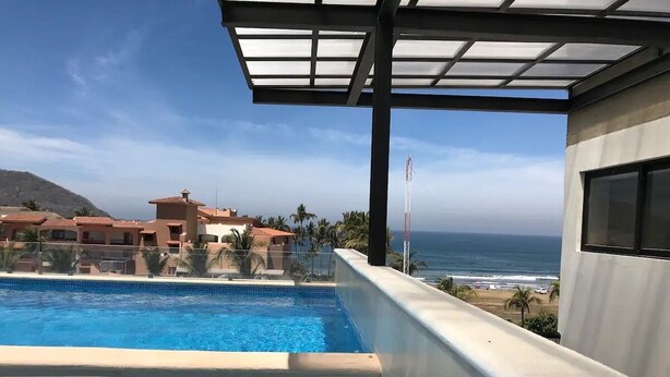 Una piscina en la azotea con vista al océano y edificios cercanos.