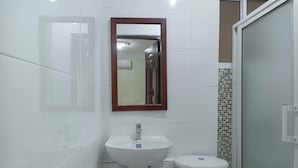 Baño con lavamanos blanco, espejo y retrete.